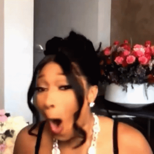 A Woman Is Making A Funny Face In Front Of A Vase Of Flowers . GIF