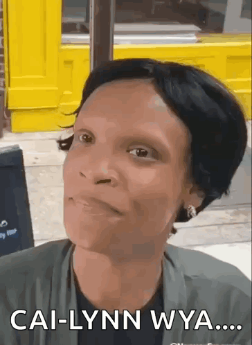 A Woman Is Making A Funny Face In Front Of A Yellow Building And Says Cal-Lynn Wya . GIF