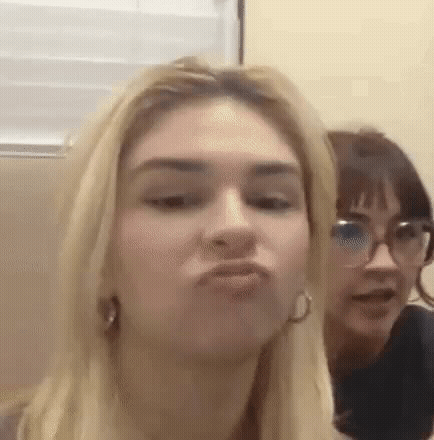 A Woman Is Making A Funny Face While Another Woman Looks On . GIF