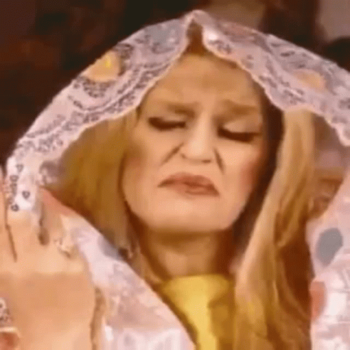 A Woman Is Making A Funny Face While Covering Her Head With A Blanket . GIF