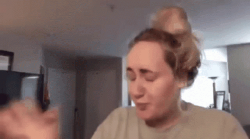 A Woman Is Making A Funny Face While Holding A Cell Phone In A Living Room . GIF