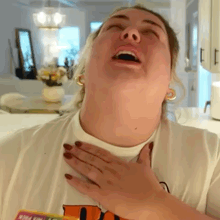 A Woman Is Making A Funny Face While Holding Her Chest . GIF
