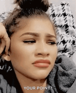 A Woman Is Making A Funny Face While Laying On A Bed And Covering Her Ears . GIF