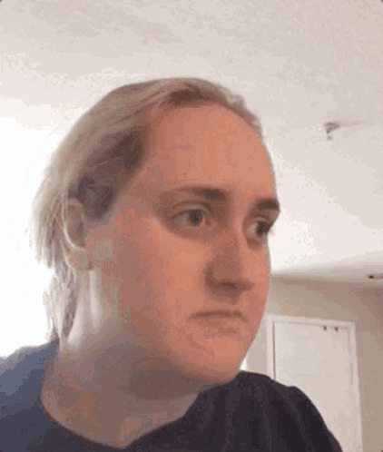 A Woman Is Making A Funny Face While Looking At The Camera In A Room . GIF