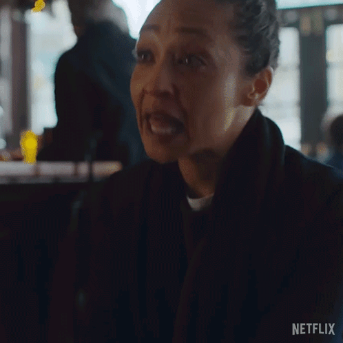 A Woman Is Making A Funny Face While Sitting At A Table In A Bar . GIF