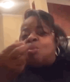 A Woman Is Making A Funny Face While Sitting On A Couch In A Room . GIF