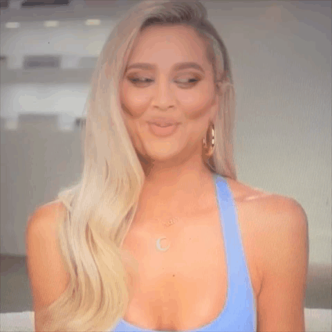 A Woman Is Making A Funny Face While Wearing A Blue Tank Top And Earrings . GIF
