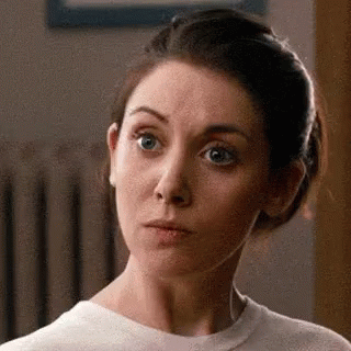 a woman is making a funny face while wearing a white shirt .