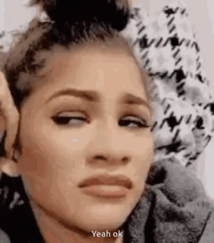 A Woman Is Making A Funny Face With Her Eyes Closed And A Bun In Her Hair . GIF