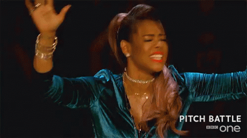 A Woman Is Making A Funny Face With Her Hands In The Air While Wearing A Blue Jacket . GIF