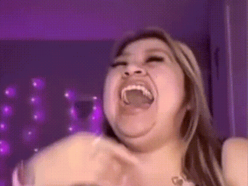 a woman is making a funny face with her mouth open and purple lights in the background .