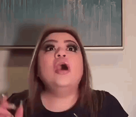 a woman is making a funny face with her mouth open in front of a picture .