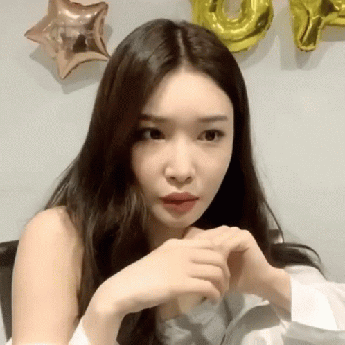 A Woman Is Making A Heart Shape With Her Hands In Front Of Balloons . GIF
