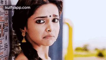 A Woman Is Making A Sad Face While Standing In Front Of A Wall . GIF