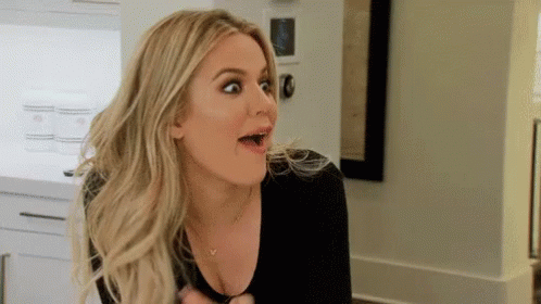 A Woman Is Making A Surprised Face In A Kitchen While Wearing A Black Shirt . GIF