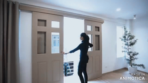 A Woman Is Opening A Sliding Glass Door Made By Animatica GIF