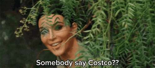 A Woman Is Peeking Out From Behind A Tree And Smiling While Saying Somebody Say Costco ? GIF