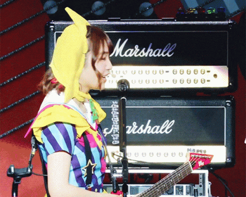 A Woman Is Playing A Guitar In Front Of A Marshall Amp GIF