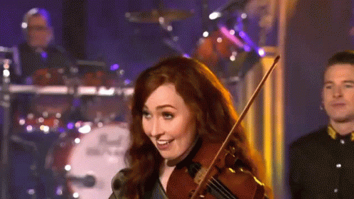 A Woman Is Playing A Violin In Front Of A Drum Set That Says Dw GIF