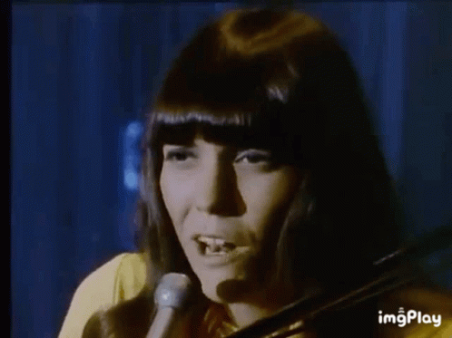A Woman Is Playing A Violin In Front Of A Microphone . GIF