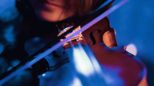 A Woman Is Playing A Violin With A Blue Light Behind Her GIF