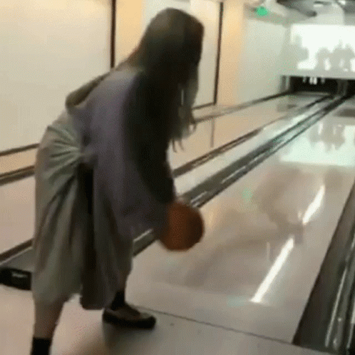 A Woman Is Playing Bowling With A Bowling Ball . GIF