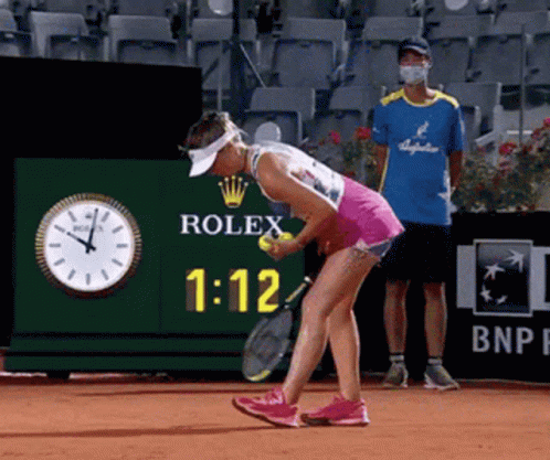 A Woman Is Playing Tennis In Front Of A Rolex Clock GIF