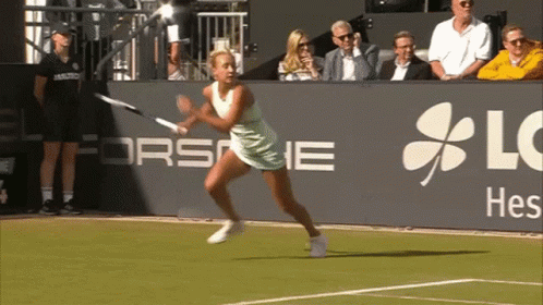 A Woman Is Playing Tennis In Front Of A Sign That Says Lg Hes GIF