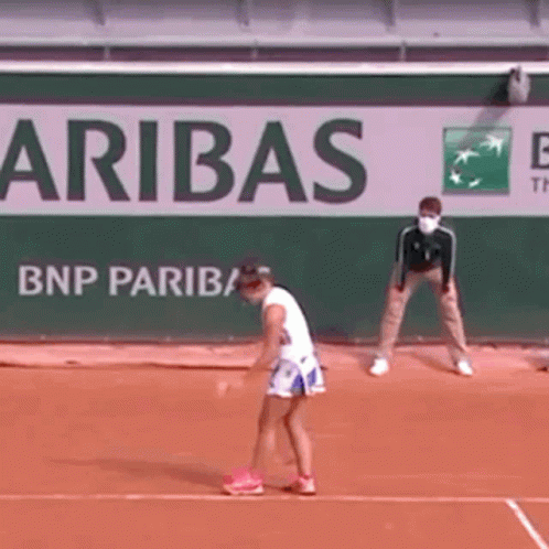 A Woman Is Playing Tennis On A Court In Front Of A Bnp Paribas Sign . GIF