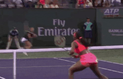 A Woman Is Playing Tennis On A Court With A Fly Emirates Banner Behind Her GIF