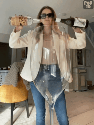 A Woman Is Pouring A Bottle Of Wine Into A Large Wine Glass That Says Por 10 On The Bottom GIF