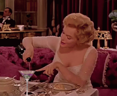 A Woman Is Pouring A Martini From A Bottle GIF