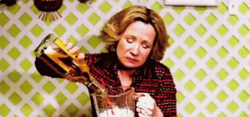 A Woman Is Pouring Alcohol Into A Pitcher . GIF