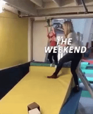 A Woman Is Pushing A Child On A Slide With The Words `` The Weekend '' Written On It . GIF