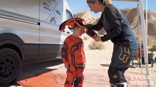 Woman Putting Helmet On Child In Front Of Cycle World Van GIF