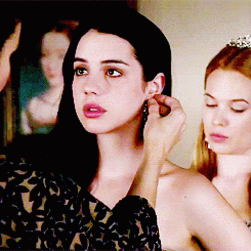 A Woman Is Putting Earrings On Another Woman GIF