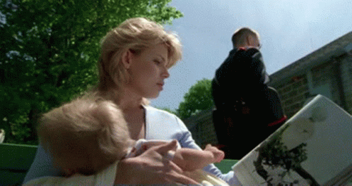 A Woman Is Reading A Book To A Baby While Another Child Looks On GIF