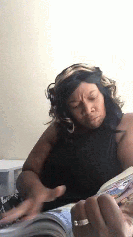 A Woman Is Reading A Magazine And Making A Face GIF