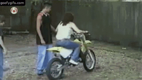 A Woman Is Riding A Dirt Bike And A Man Is Standing Next To Her . GIF