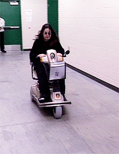 A Woman Is Riding A Scooter That Has The Number 7 On It GIF