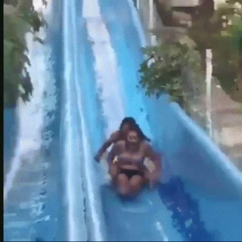 A Woman Is Riding On The Back Of A Man On A Water Slide GIF