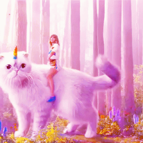 A Woman Is Riding On The Back Of A White Cat With A Unicorn Horn On Its Head GIF