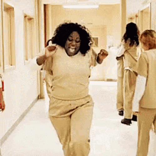 A Woman Is Running Down A Hallway In A Hospital While A Group Of Women Are Standing Behind Her . GIF