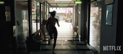 A Woman Is Running Down A Hallway With A Netflix Logo In The Corner GIF
