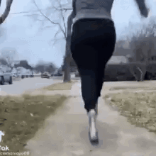A Woman Is Running Down A Sidewalk With A Dog In Her Arms . GIF