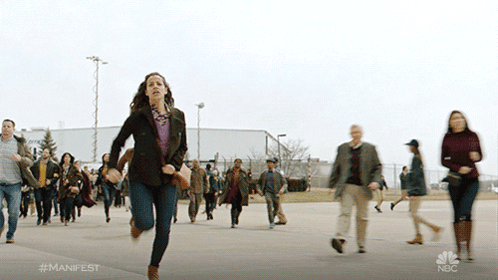 A Woman Is Running In Front Of A Crowd With The Hashtag #Manifest On The Bottom GIF