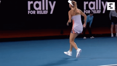 A Woman Is Running On A Tennis Court With A Rally For Relief Banner Behind Her GIF