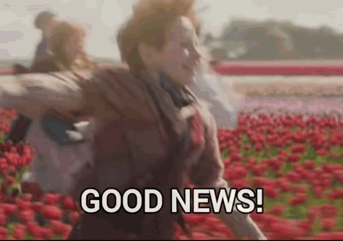A Woman Is Running Through A Field Of Red Flowers And Says `` Good News '' . GIF