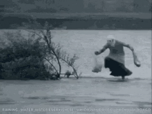 A Woman Is Running Through A River Carrying A Bag Of Food . GIF