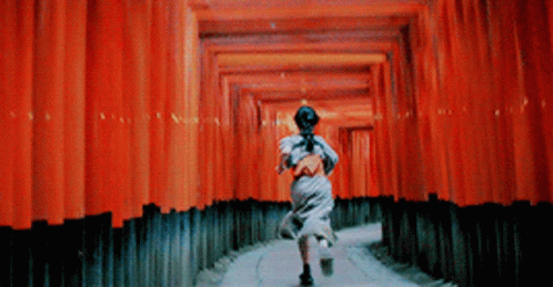 A Woman Is Running Through A Tunnel Of Red Walls GIF